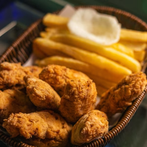 Crispy fried chicken pieces paired with thick-cut golden fries and a creamy dip, served in a classic wicker basket.