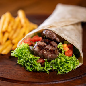 Soft flour tortilla stuffed with chargrilled kofta patties, fresh lettuce, and diced tomato, served alongside golden fries.